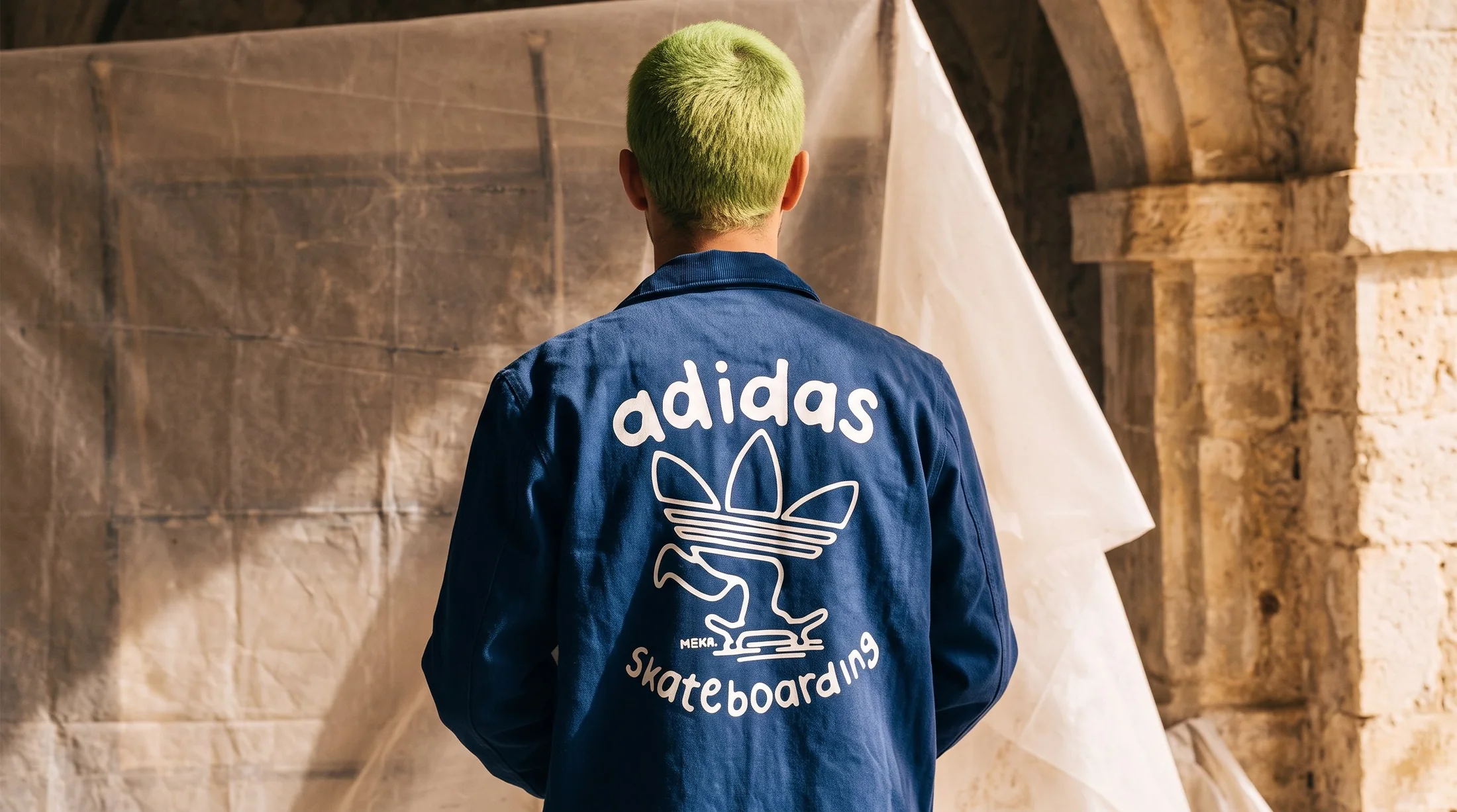 adidas Skateboarding coach jacket worn from the back, hand-drawn trefoil-skater graphic with the MEKA. signature, sunlit stone setting