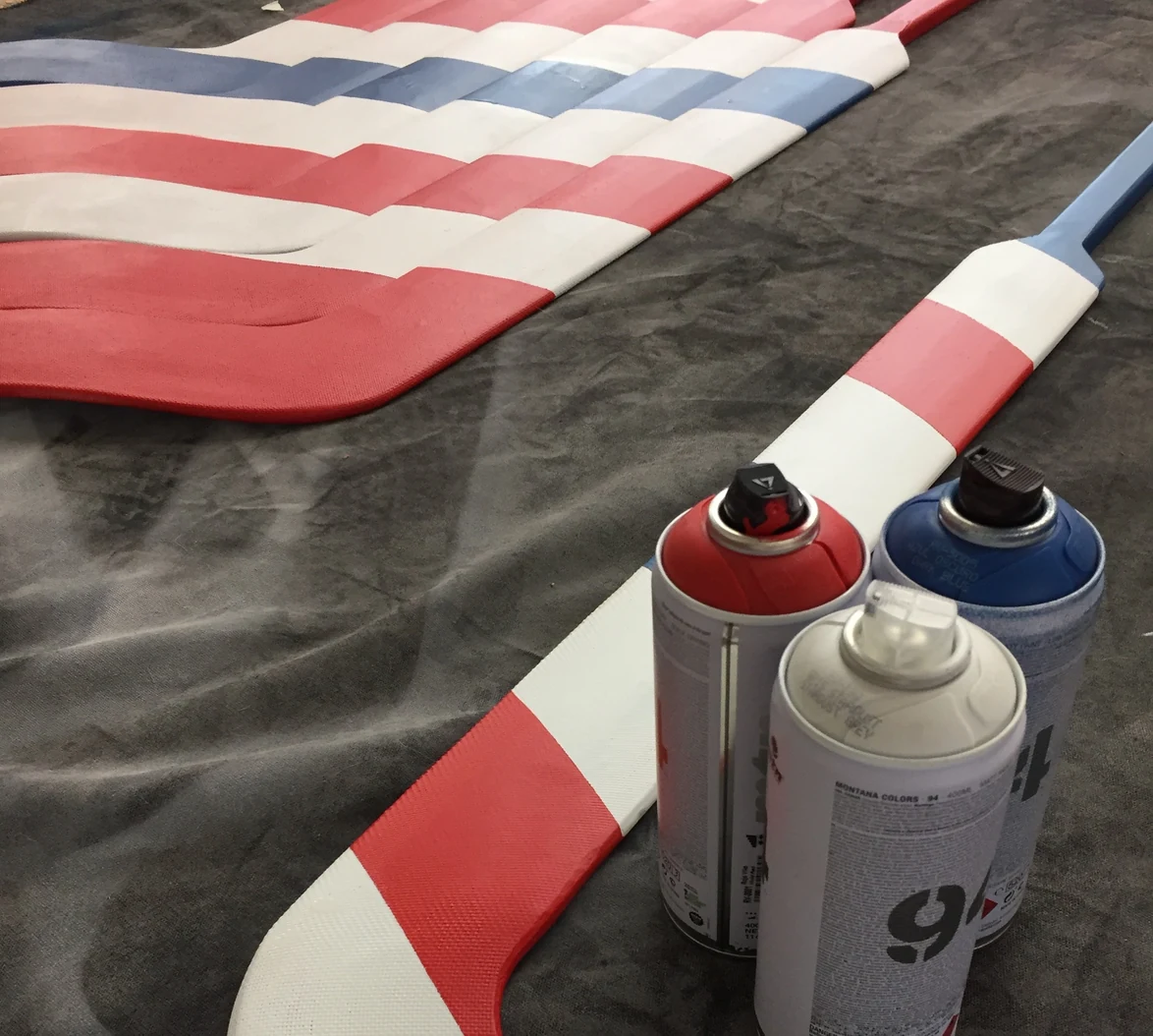 Goalie sticks laid out mid-paint, cans beside them