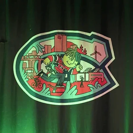The crest lit in green on stage at the Vert le but launch