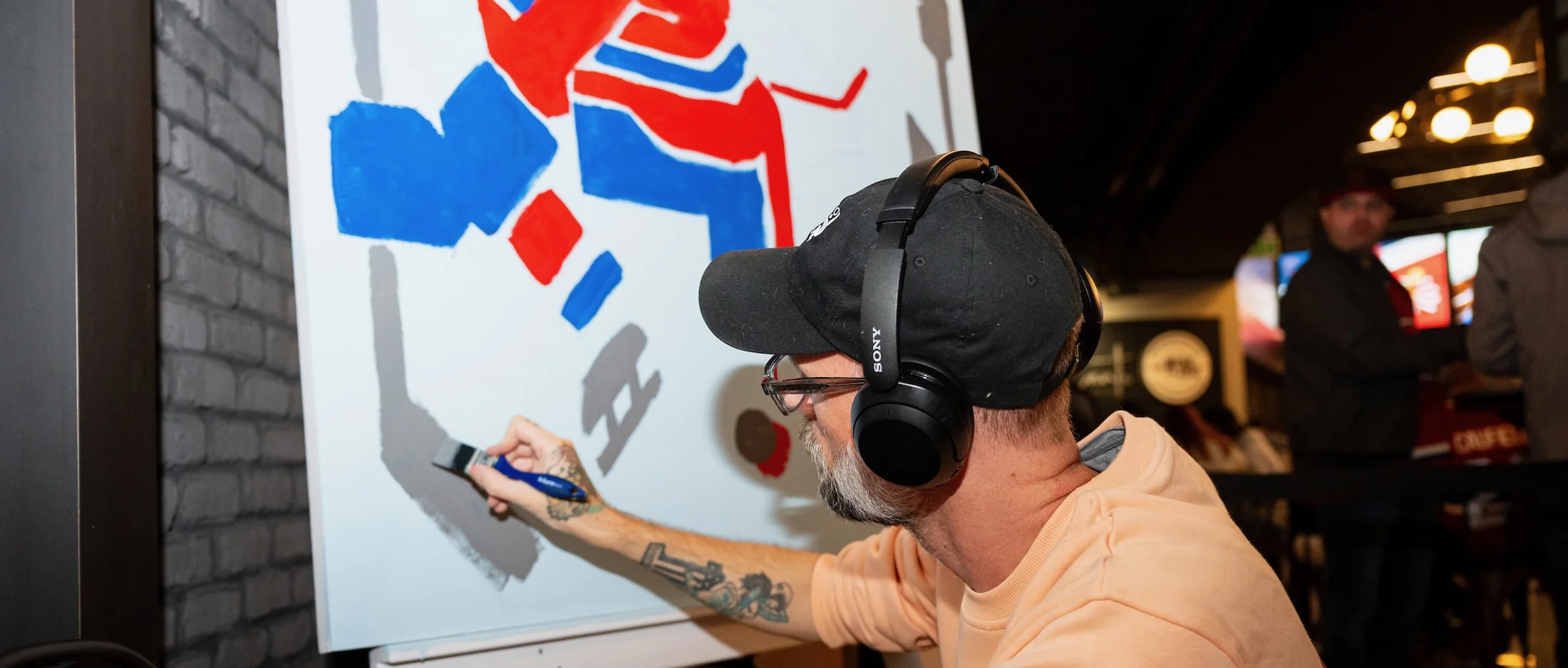 Painting the canvas live, headphones on, spectators behind