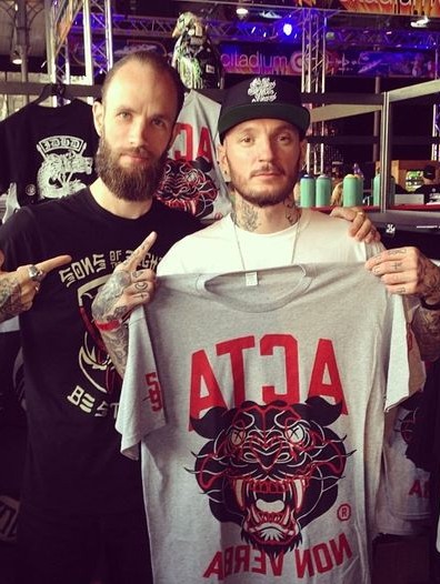 Two of the crew holding up the Acta Non Verba tee at the shop