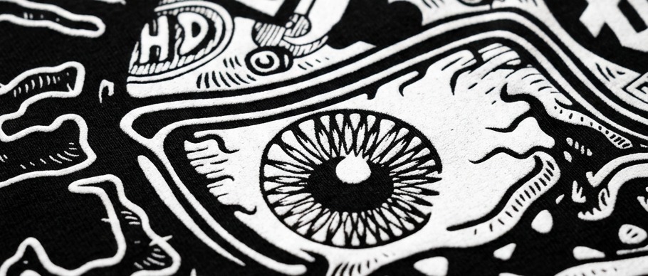 Screen print detail on black cotton — the eye at the centre of the Idlehand graphic