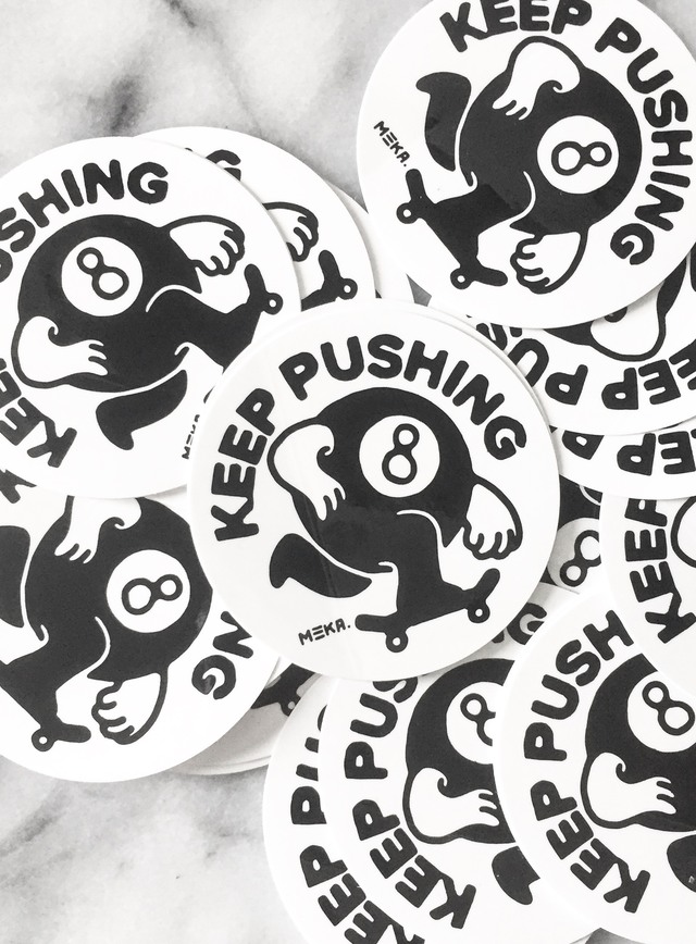 A pile of Keep Pushing stickers, eight-ball character