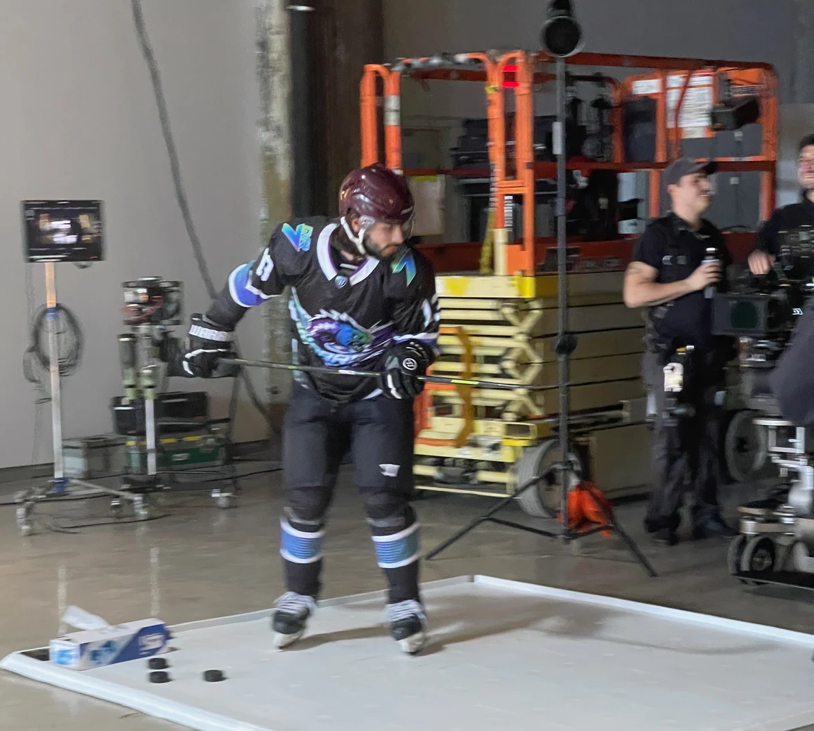 A skater in Warrior gear on the white floor, crew and scissor lift behind him