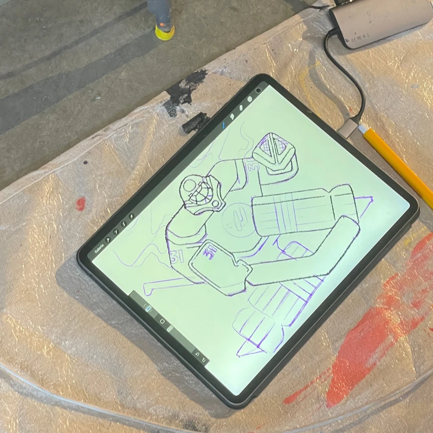 The goalie drawn in line on a tablet, propped on a paint-splattered stool
