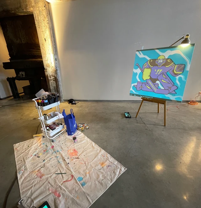 The easel and the drop cloth alone on the studio floor before the take